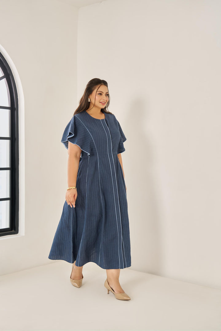 Light blue cotton Elara dress with subtle piping, ruffled cap sleeves, concealed buttons, and adjustable back belt for a flattering plus-size fit