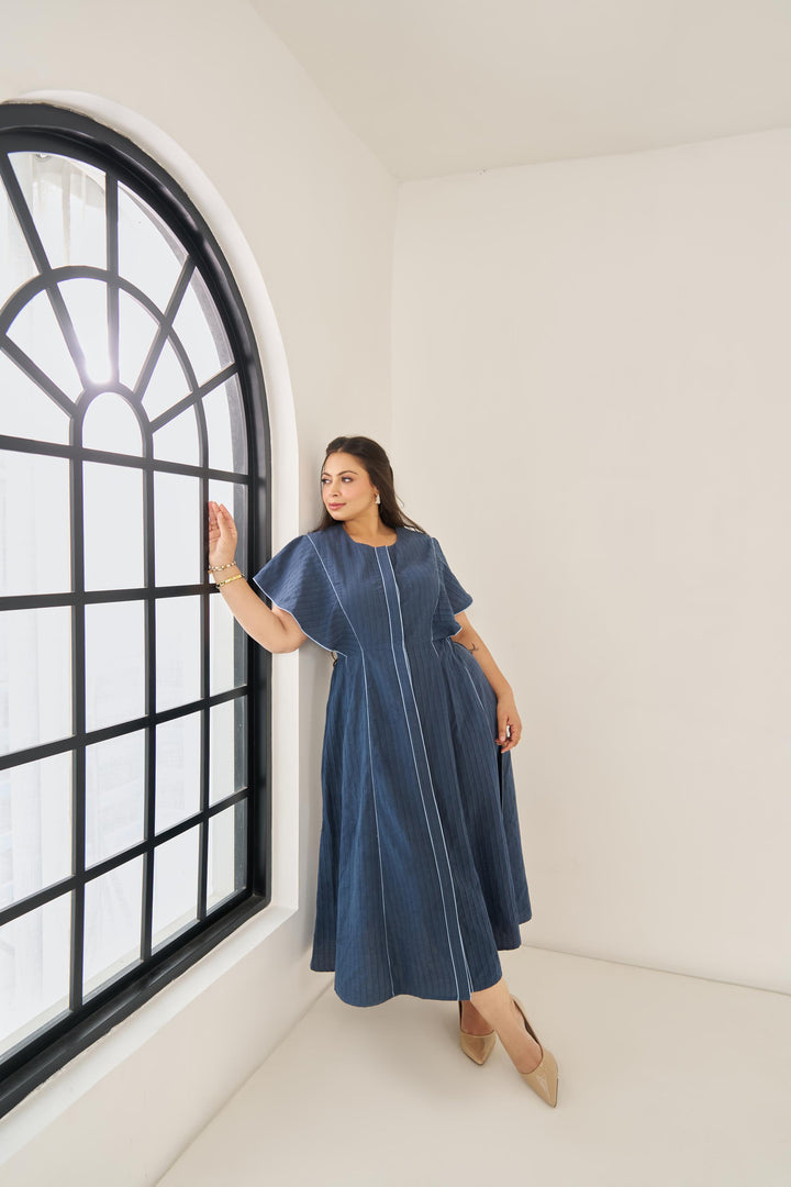Light blue cotton Elara dress with subtle piping, ruffled cap sleeves, concealed buttons, and adjustable back belt for a flattering plus-size fit